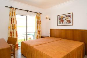 a bedroom with a bed and a large window at Apartamentos Benvindo in Albufeira
