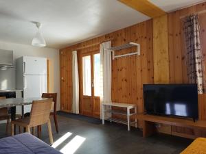 een woonkamer met een televisie en een tafel en een keuken bij Appartement RDC chalet 55m2 in Briançon