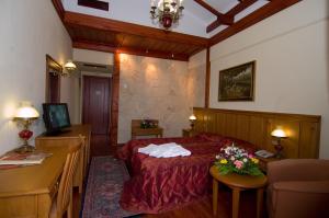 Un dormitorio con una cama y una mesa con flores. en Hotel Aiges Melathron, en Veria