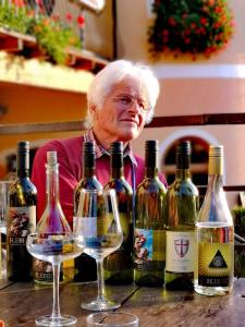 an older woman sitting at a table with wine glasses at Turistična kmetija HLEBEC in Kog