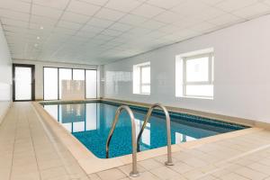 a large swimming pool with blue water in a building at Aparthotel Adagio Access Paris Clamart in Clamart