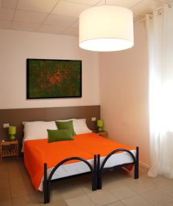 a bedroom with an orange bed with a painting on the wall at Como Rooms & Apartments T.10 in Como