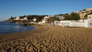 una playa de arena con edificios blancos y el océano en A 20 mt dal mare con ombrellone e sdraio in spiaggia, en Castiglioncello