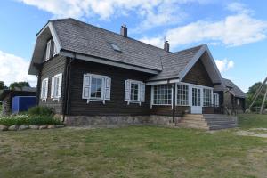 a wooden house with white windows on a yard at Labanoro troba in Labanoras