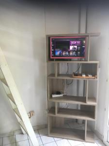 a tv on a shelf in a room at à pied dans l eau écolo 97434 in L'Ermitage-Les-Bains