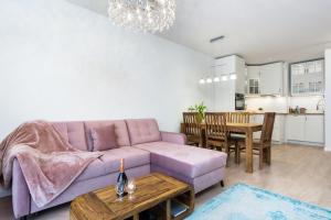 a living room with a purple couch and a table at Elite Apartments Marine Cztery Oceany in Gdańsk