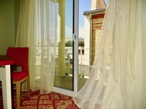 a room with a window with curtains and a red chair at Mercure Paris Pont de Levallois Neuilly in Levallois-Perret