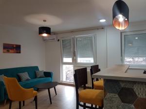 ein Wohnzimmer mit einem Tisch, Stühlen und Fenstern in der Unterkunft Apartman Simić 2 in Valjevo