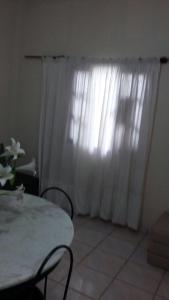a room with a table and a white curtain at 3 Kitnets in Rio das Ostras