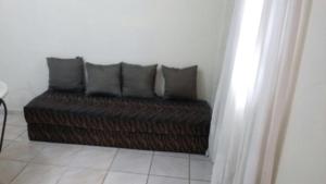 a brown couch with four pillows in a room at 3 Kitnets in Rio das Ostras