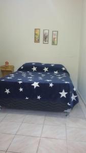 a bed in a room with a blanket with stars on it at 3 Kitnets in Rio das Ostras