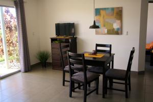comedor con mesa, sillas y TV en Apartamentos La Alborada Airport SJO, en Alajuela