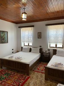 two beds in a room with white walls and windows at Guest House Iljesa in Berat
