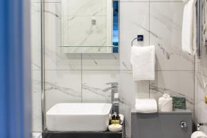 Baño blanco con lavabo y espejo en Limestone Hotel, en Lulworth Cove