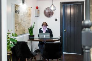 a woman sitting at a table with a laptop computer at Limestone Hotel in Lulworth Cove