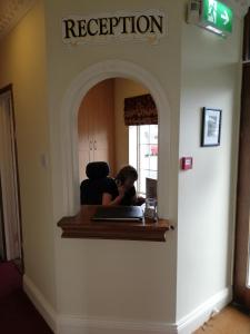 a woman sitting at a reception desk in a room at Castle Lodge in Killarney