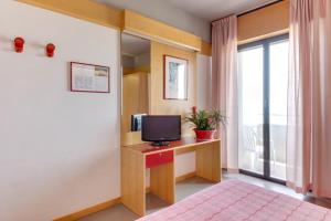 a bedroom with a bed and a desk with a television at Hotel Giglio in Rimini