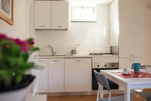 a kitchen with white cabinets and a white table with a tableablish at San Pietro Holiday House in Scala