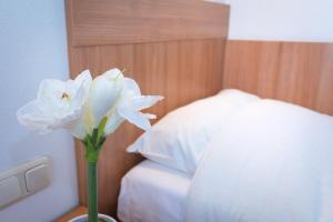 a white flower in a vase next to a bed at B&B Restaurant Maria Johanna Hoeve in Noordeloos