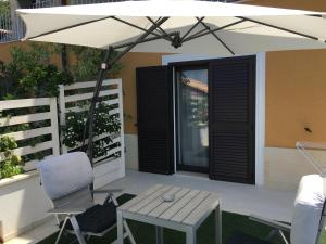 a white umbrella on a patio with a table and a chair at Residenza RoMa in Tropea