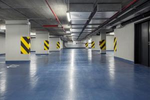 an empty parking garage with yellow and black arrows on the walls at Urban Creme in Prague