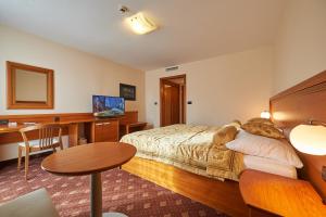 a hotel room with a bed and a desk and a table at Hotel Korosica in Šentjanž pri Dravogradu