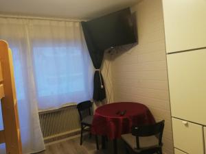 Pokój z czerwonym stołem i krzesłami oraz telewizorem w obiekcie Apart Family Schweng w mieście Tux
