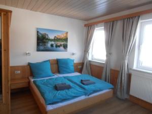 a bedroom with a bed with blue sheets and windows at Restaurant Olympia & Apartments in Bergen