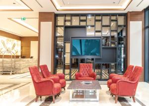 a lobby with red chairs and a tv at Ramada Beylikduzu in Istanbul