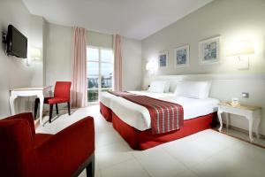 サンルカル・ラ・マヨールにあるExe Gran Hotel Solucarのベッドと椅子付きのホテルルーム