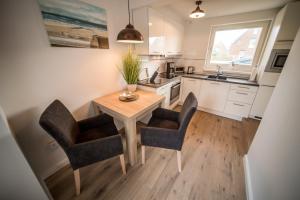 a kitchen with a wooden table and two chairs at Haus Sonnenterrasse in Westerland