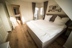 a bedroom with a large bed with white sheets and pillows at Haus Sonnenterrasse in Westerland