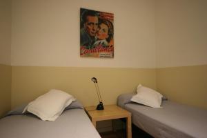 two beds in a room with a movie poster on the wall at Az Barcelona Center in Barcelona