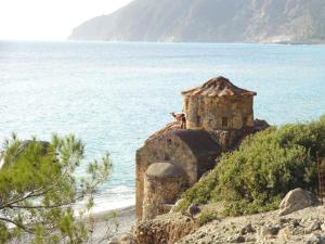 
a large stone building with a view of the ocean at Gigilos in Agia Roumeli
