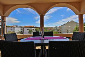 a table with wine glasses on a balcony at Apartments Tony in Biograd na Moru