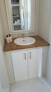 ein Badezimmer mit einem weißen Waschbecken und einem Spiegel in der Unterkunft Nova Skye in Johannesburg