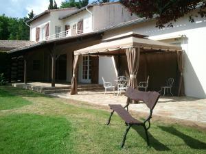 a chair in front of a house with an umbrella at Mas du Trezon in Cholet