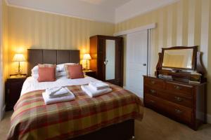
a hotel room with a bed and a dresser at Craigroyston House in Pitlochry
