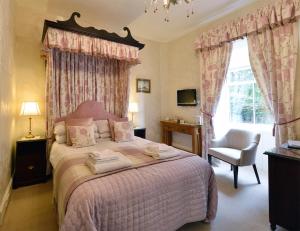 a bedroom with a pink bed with a chair and a window at Craigroyston House in Pitlochry
