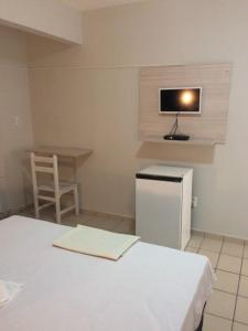 a room with a refrigerator and a table and a tv at Hotel Mundial in Patos