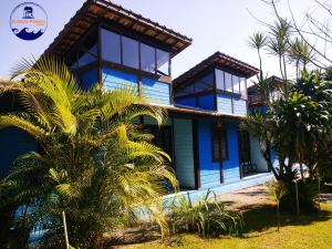 a blue house with a palm tree in front of it at Estacao Paraiso Chalé in Bertioga