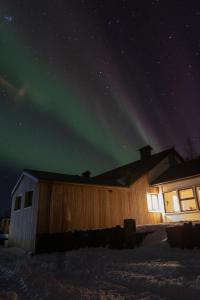 a building with the aurora in the sky behind it at Dalshöfdi Guesthouse in Dalshöfdi