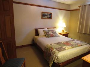 um quarto com uma cama com um candeeiro e uma mesa em Carlson's Lodge em Twin Mountain