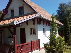 a white house with a red fence and a christmas tree at Fácánkert Apartmanház in Tiszafüred