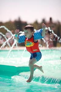 a young boy jumping on a wave in the water at Centre de Villégiature Dam-en-Terre in Alma