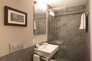 
a bathroom with a sink, toilet and mirror at Hotel Steffani in St. Moritz
