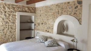 a bedroom with a bed and a stone wall at Vista de la Vila - Turismo de interior. in Llubí