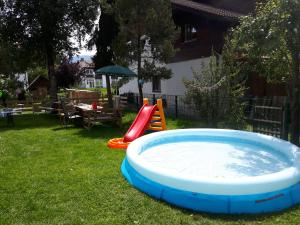 a hot tub in a yard with a slide and a playground at Haus Bayrhof in Hopferau