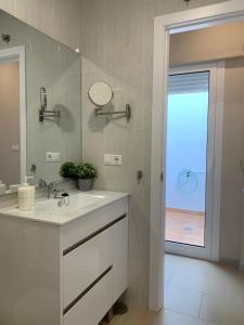 łazienka z białą umywalką i lustrem w obiekcie APARTAMENTO MARIPOSA II w mieście Conil de la Frontera