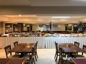 um restaurante com mesas de madeira e um buffet de comida em Hotel Recanto Do Rouxinol em Piratuba